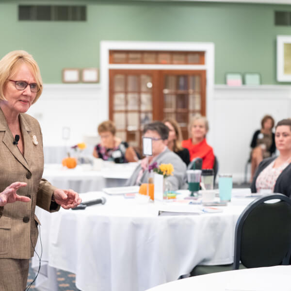 woman presenting talking to people at tables