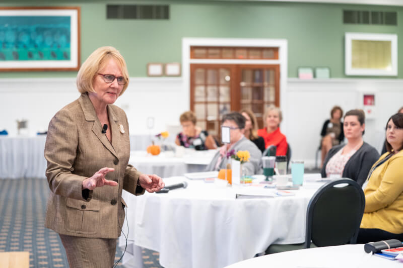 woman presenting talking to people at tables