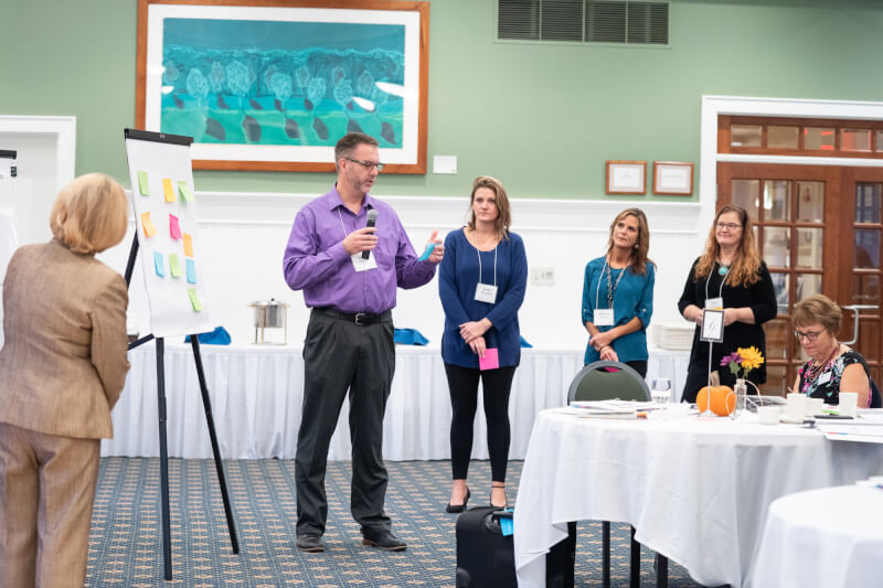 people stand in line before board on easel