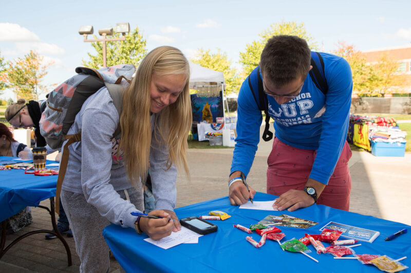 Female Student smiling while writing on a postcard