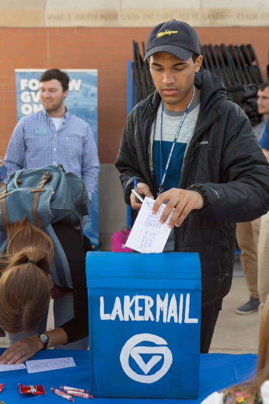  Student putting a postcard into a Laker Mail box