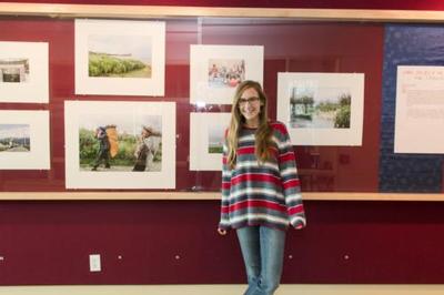 Megan Lendman, '14, poses with her exhibit "China: The Life of the Civilian," which was displayed at the Red Wall Gallery in 2014.