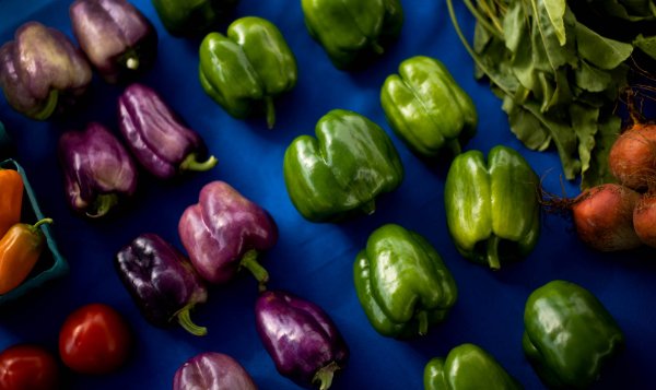 An above shot of bell peppers organized by color: red, purple, and green