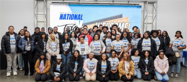 large group of students, kneeling and standing in front of GVSU Detroit Center banner