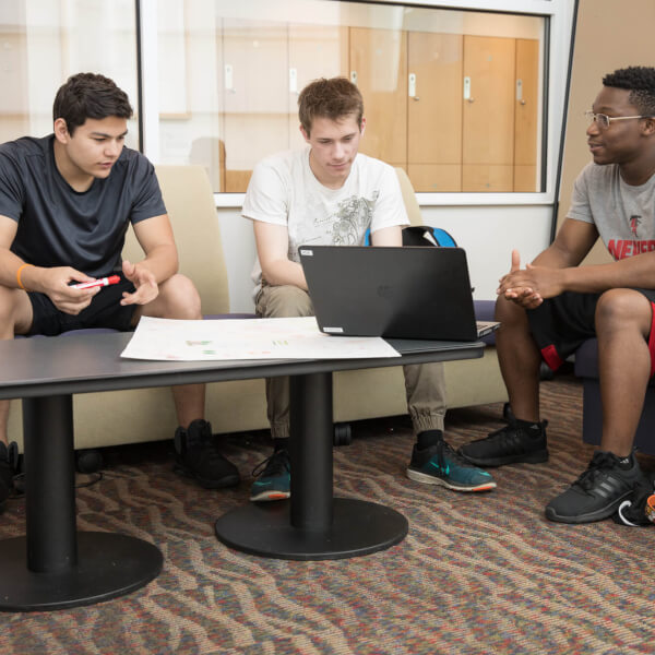 three young men talking in chairs, before computer