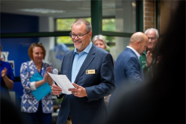 Man with microphone standing, wearing a suit jacket