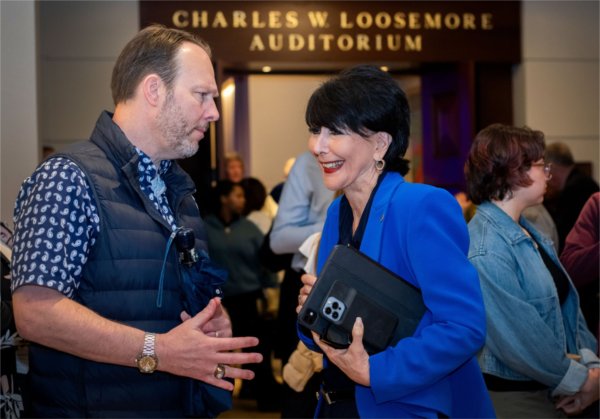 man in short sleeves and vest talking with President Mantella, dressed in blue jacket