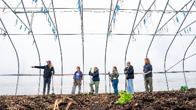 Farm manager Isak Davis and a group of student volunteers stand in a farm hoop house and prepare to plant. 