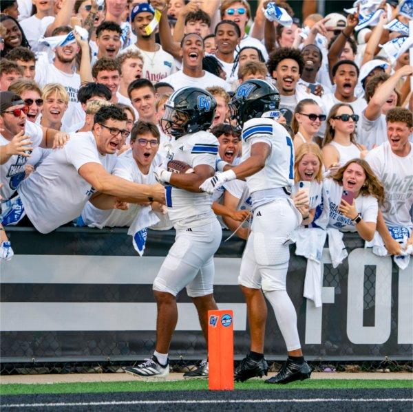 Two Grand Valley football players celebrate a touchdown with students.