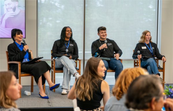 President Mantella sits on stage with three students who speak in a panel. 