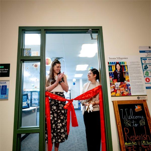 Mimi Sperl and Susana Villagomez stand in the doorway of Replenish behind a red ribbon tied in a bow.