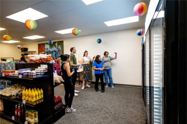 A group of people stand next to shelves in Replenish and admire the newly installed freezers. 