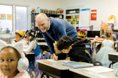 Excel Charter Academy principal Dan Bartels checks on a student during a reading exercise.