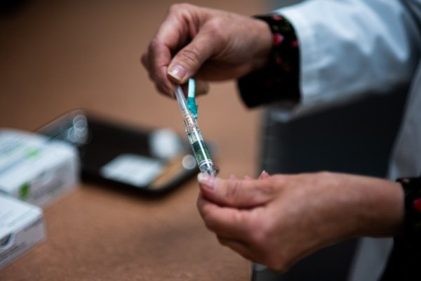 Hands holding a syringe with a flu vaccine in it