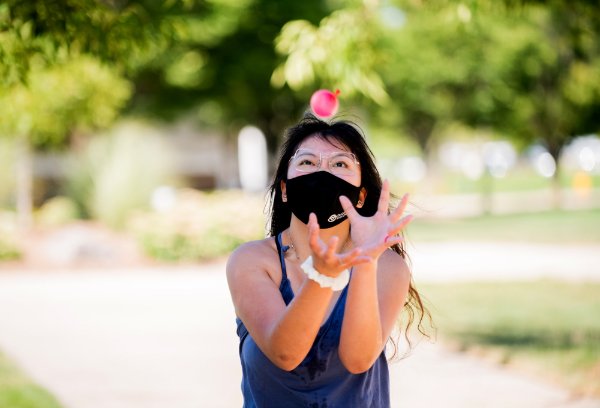 student wearing mask prepares to catch a water balloon