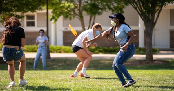 students outside playing chicken tag, wearing masks throwing a rubber chicken