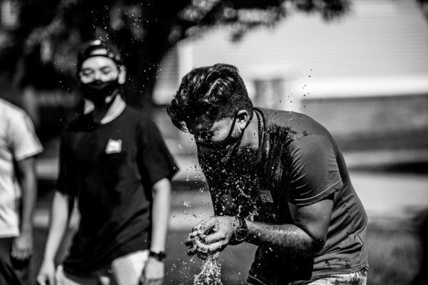 two people during a water balloon game, balloon breaks in student's face, lots of water