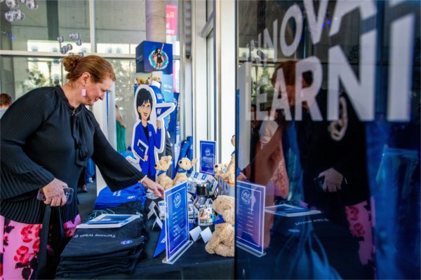 Smiling person reaches out towards a table with merchandise.