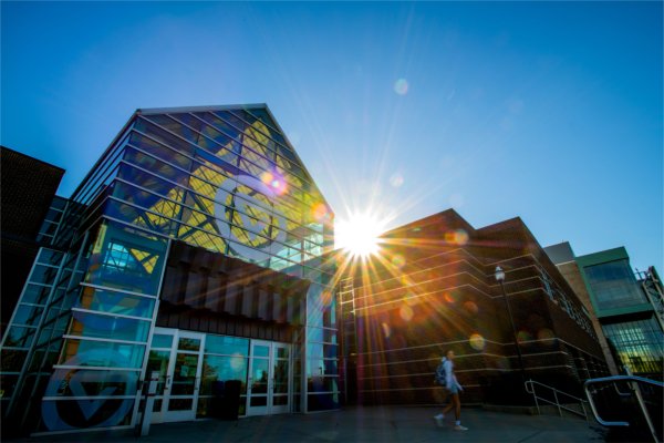 The sun sets behind a campus academic building. 
