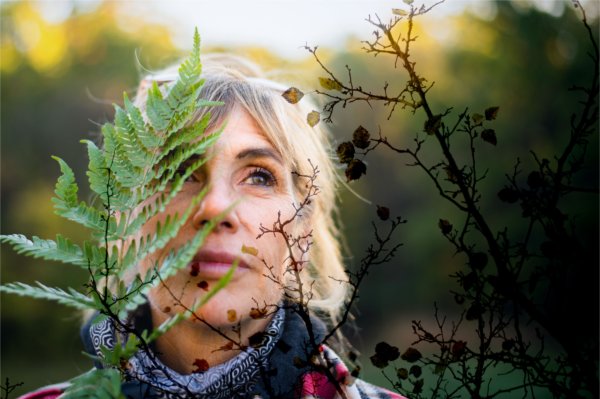 A portrait of an artist with natural elements of ferns and plants surrounding their face. 