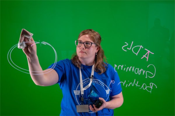 A person demonstrates a lightboard in front of a green screen. 