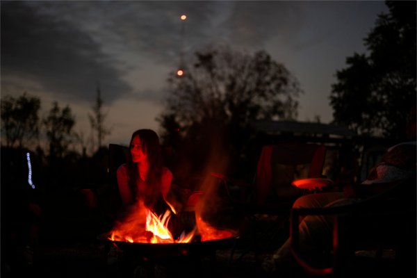 A college student glows by the light of a bonfire. 