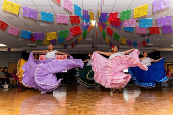 Two dancers wearing colorful flowing skirts dance.