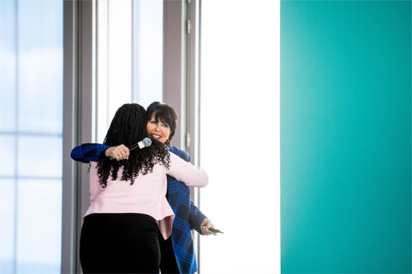 Two people embrace with light shining through a nearby window.