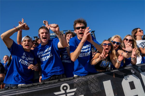A student section of students cheering wearing blue. 