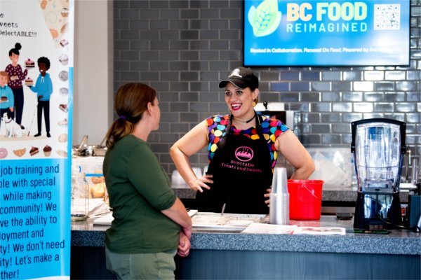 A person smiles while greeting a customer. 