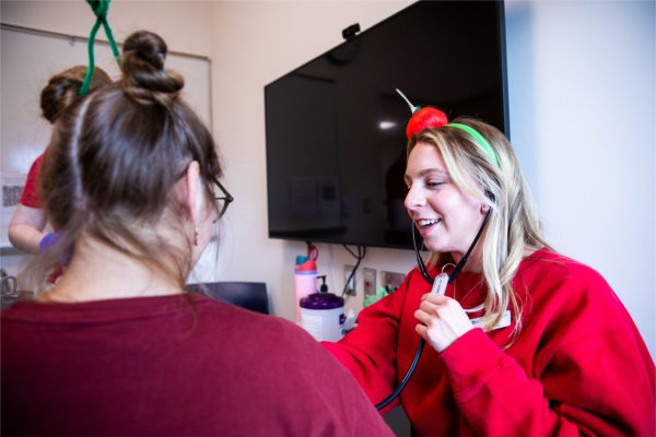 Wearing a costume, a student listens to a heartbeat using a stethoscope. 