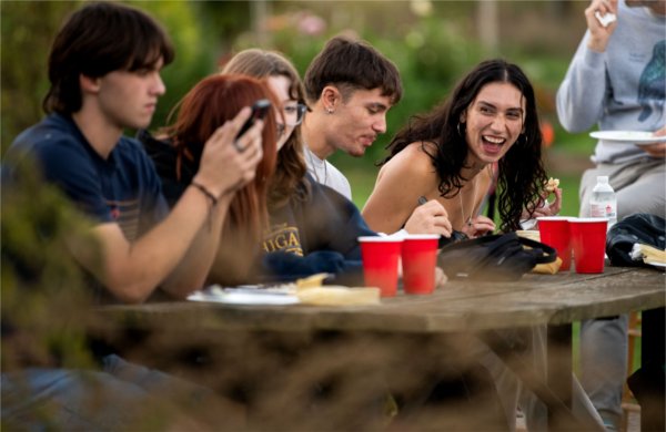 People sit at a wooden table, one laughing.