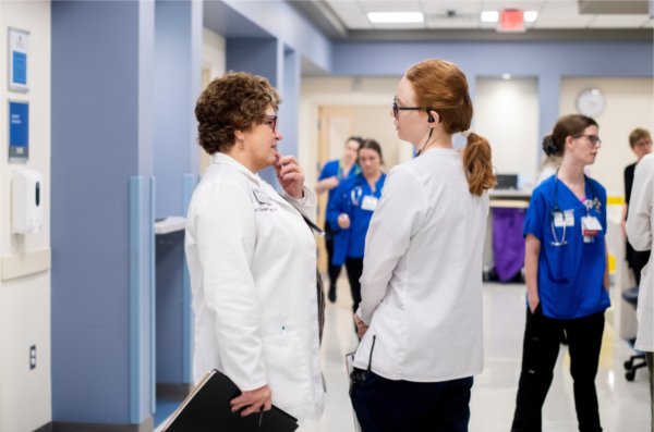 KCON faculty members Sally Stockdale, left, and Briana Hutchinson talk in the hallway of the hospital suite in the Simulation Center. Twelve faculty members and three Corewell Health nurses joined the simulation.