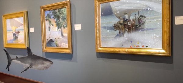 An image of a shark appears to be swimming in front of three paintings hung on a wall.