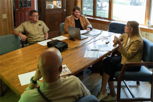 People sitting around a table in a conference room listening to a presentation.