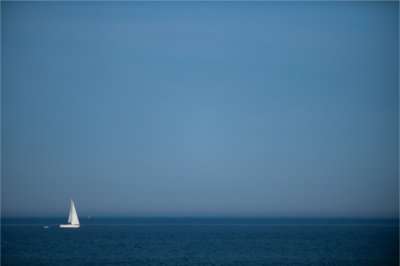 A sailboat glides along Lake Michigan past Muskegon State Park.
