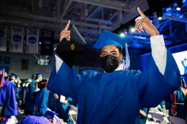 A graduate celebrates while holding their diploma