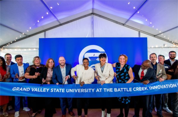 Several people cut a ribbon that says Grand Valley State University at the Battle Creek Innovation Hub.