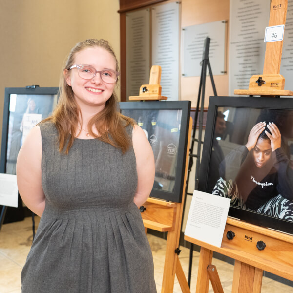 woman standing by framed photos in an exhibit
