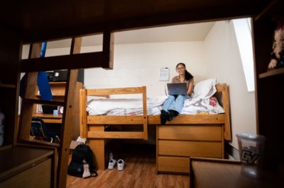 Sarah Conway sits on her loft bed in her living center room.