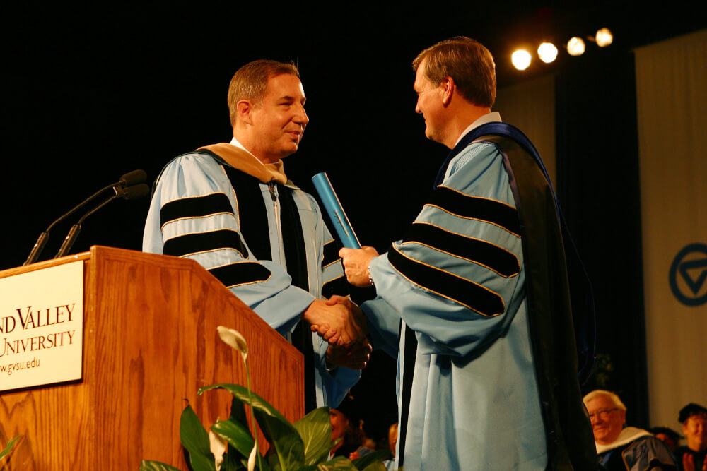 two presidents of Grand Valley in regalia with a baton