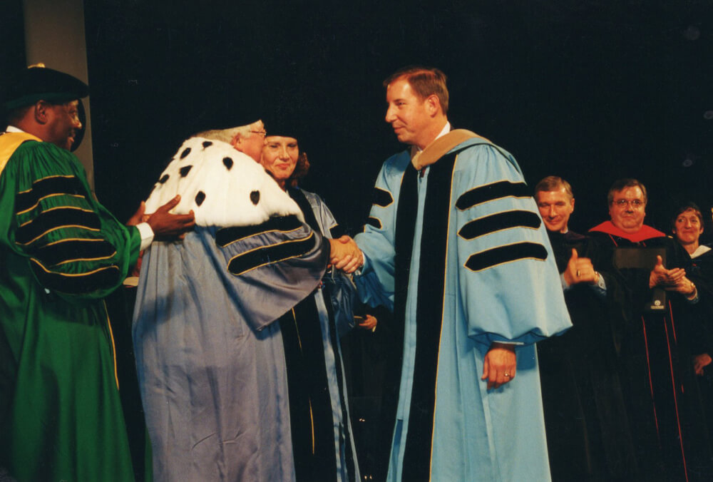 men at investiture shaking hands in regalia