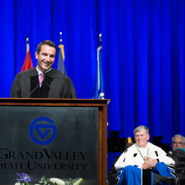 man on commencement stage, in gown