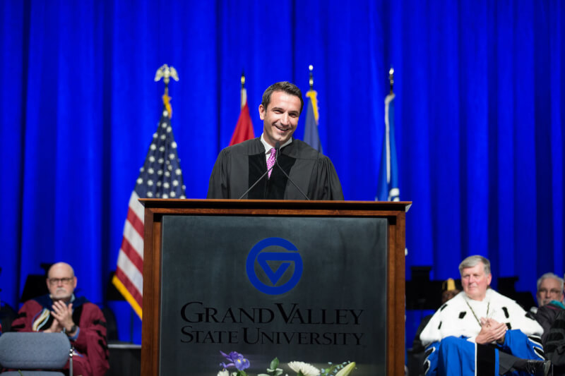 man on commencement stage, in gown