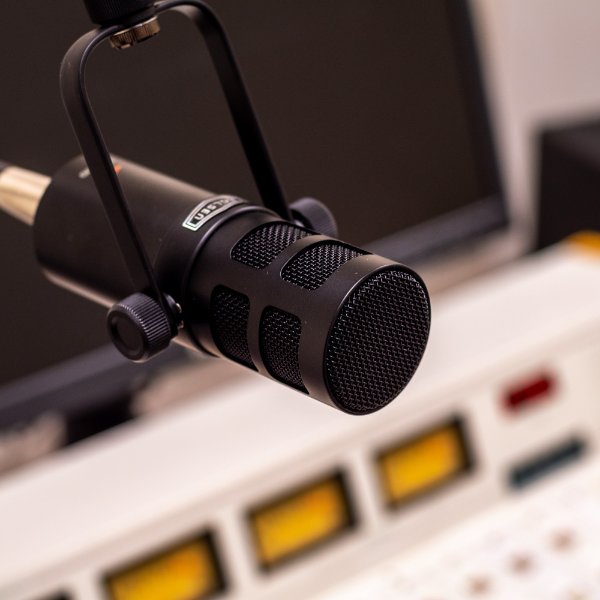 A studio microphone for a radio station hangs over the control board.