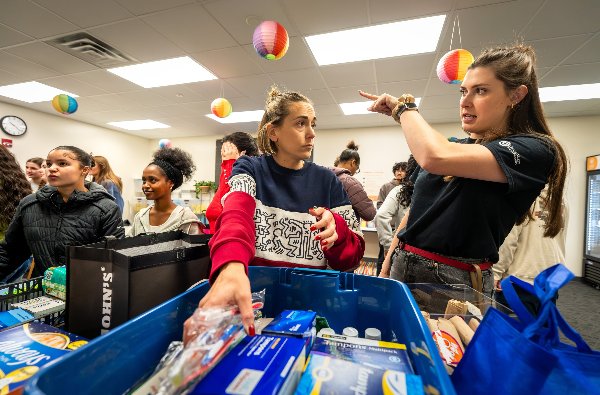 Two women discuss where to move a box full of pads and tampons in the food pantry. 