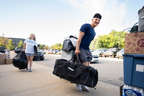 A student carries his belongings into a living center on the second day of move-in on campus.
