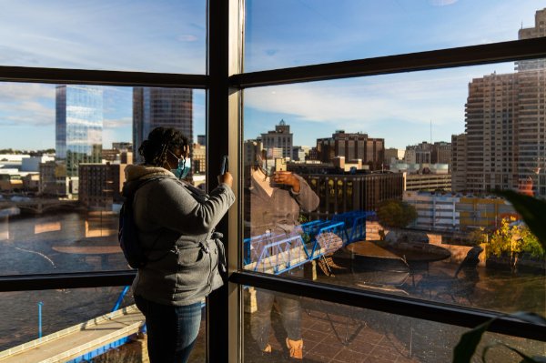 A SAU student takes a phone photo looking out windows at the Eberhard center over the Grand River