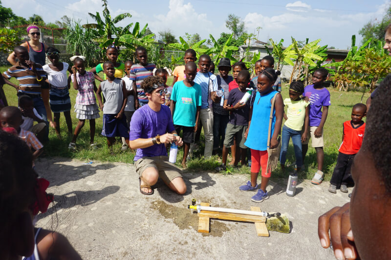 GVSU student Tyler Martin helping students build and launch water rockets in Haiti.
