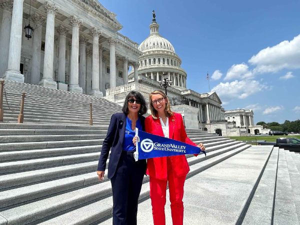 President Mantella and Representative Hillary Scholten stand on the Capitol steps together and hold a GVSU flag.